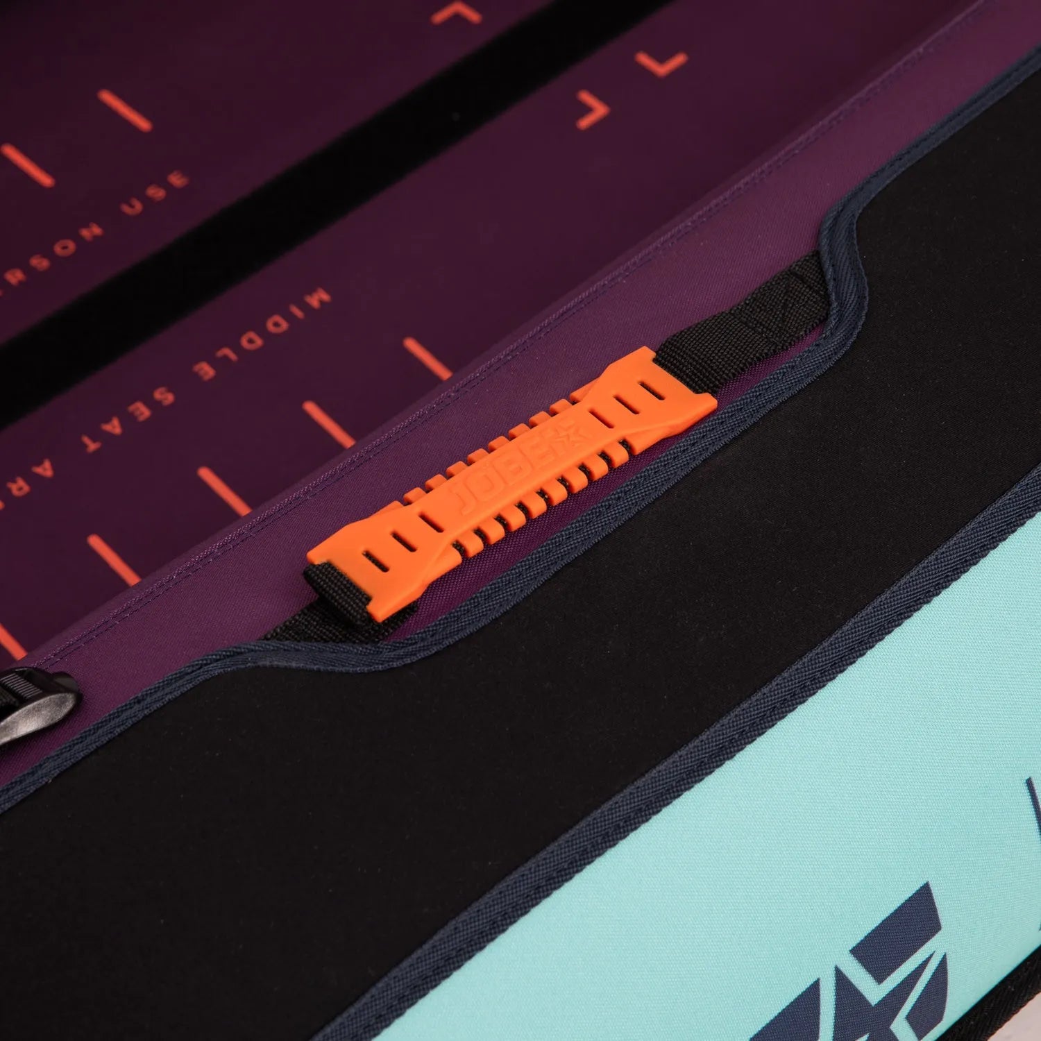 Close-up of a seat cover with an orange strap and text on a purple and black background.