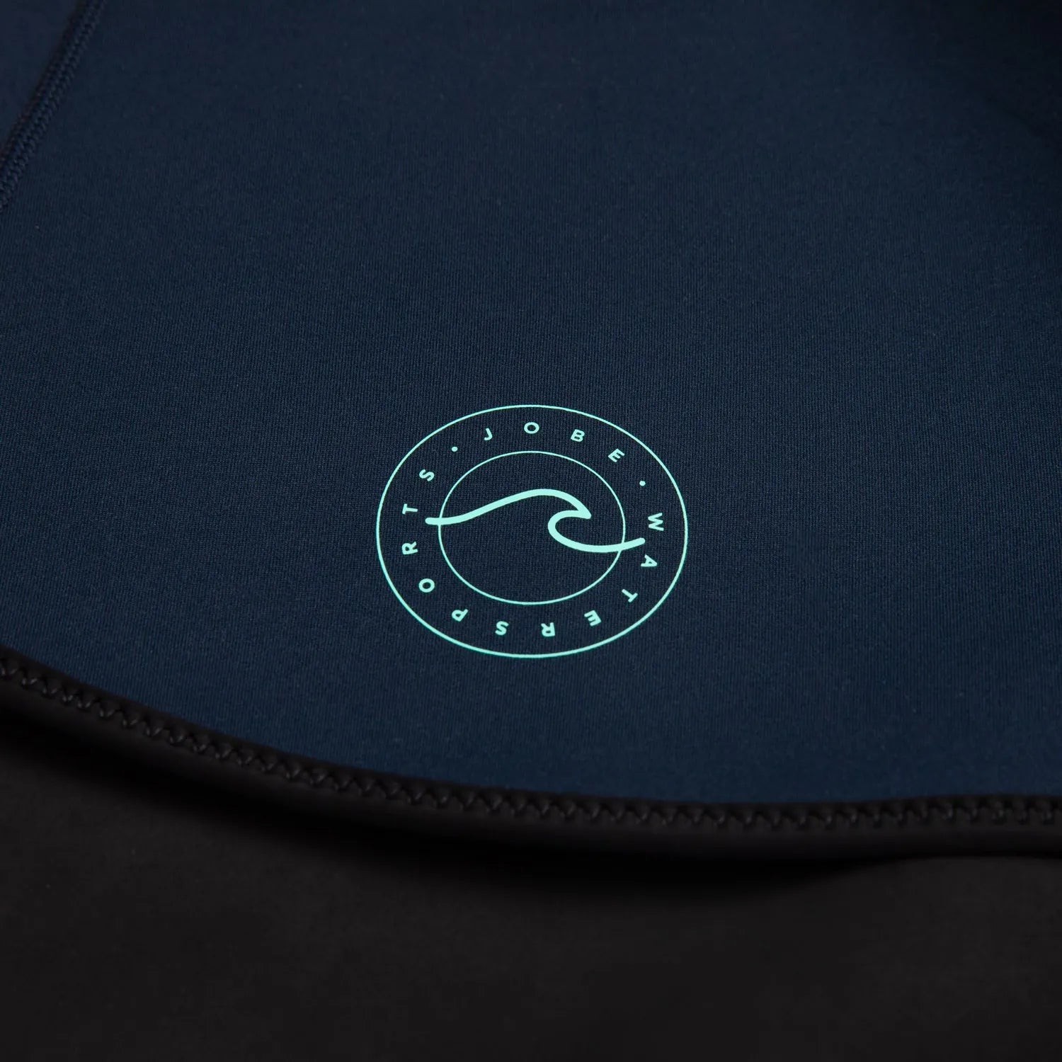 Close-up of a dark blue garment with a green logo on a black background
